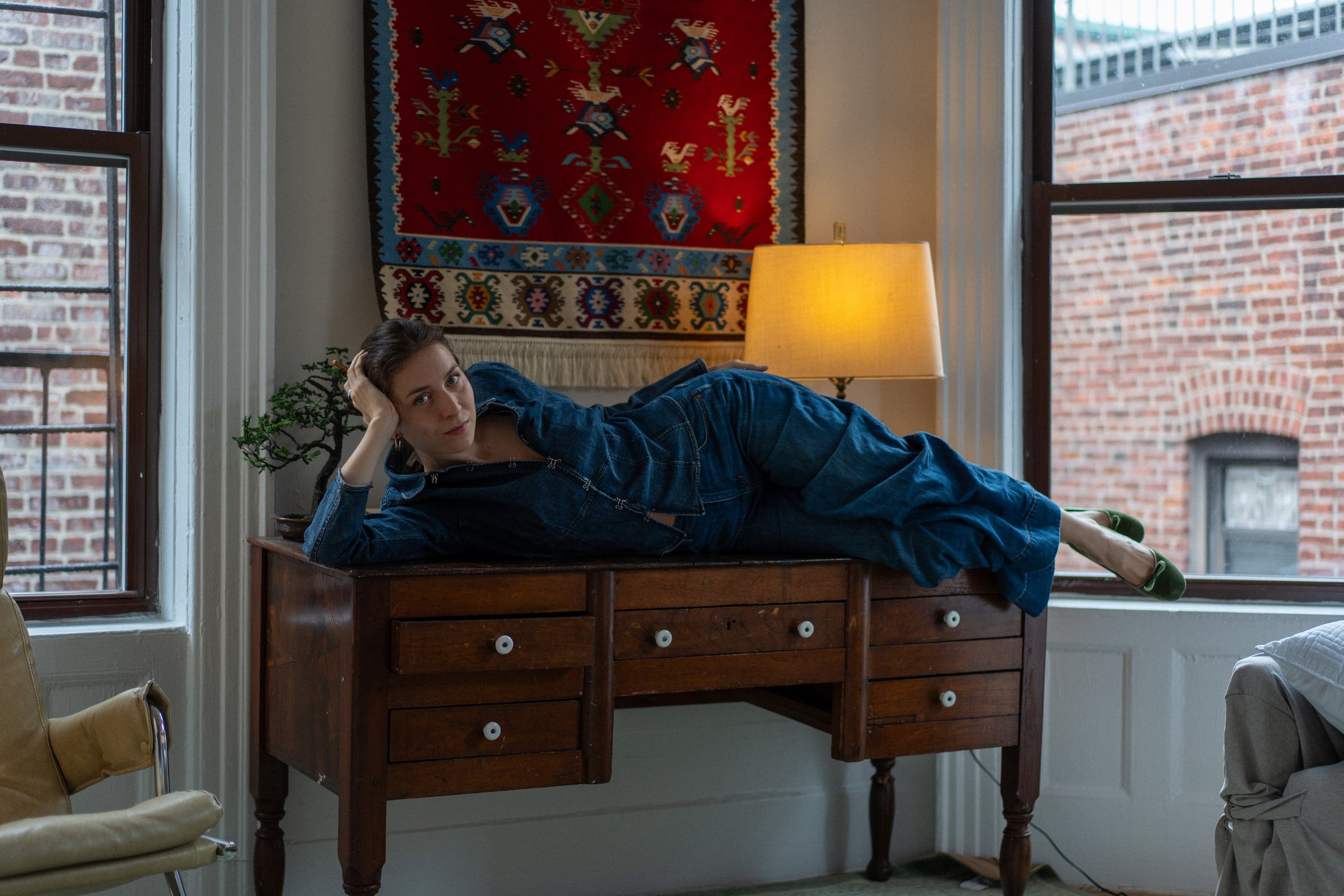 Amelia Gates reclining on a writing desk between two windows.